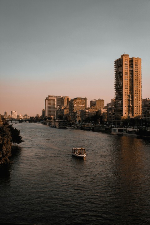 a boat traveling down a river next to tall buildings