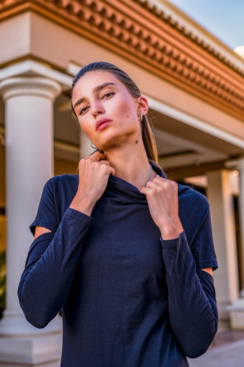 a woman standing outside of a building with her hand on her neck