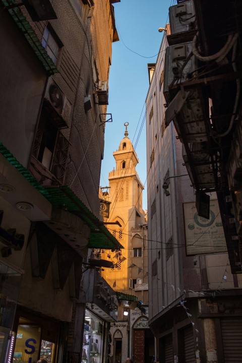 a narrow city street with a church steeple in the background rH0JUF0YF