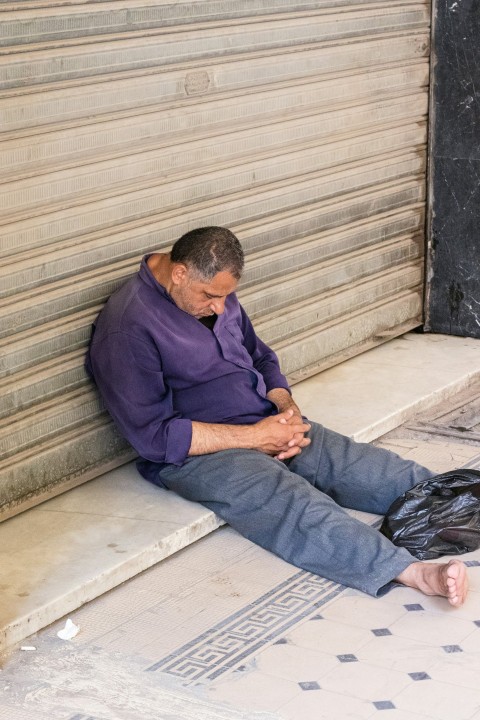 man in purple dress shirt and blue denim jeans sitting on gray concrete stairs