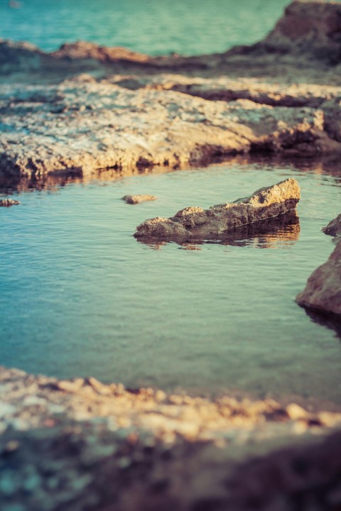 brown rock formation on body of water during daytime