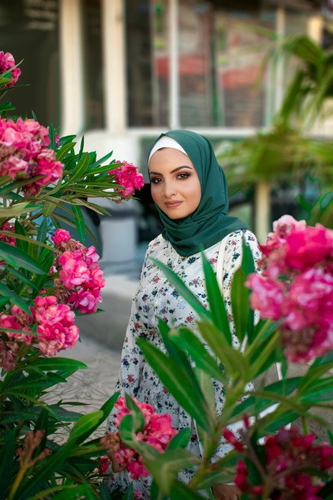 woman in white green and pink floral hijab holding pink flowers