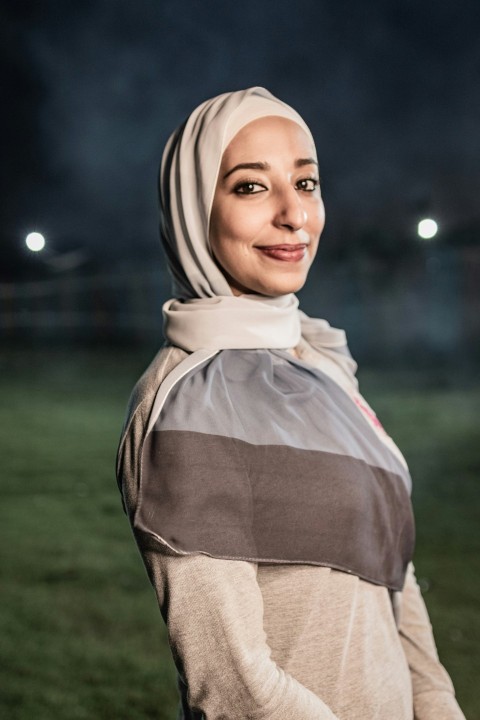 a woman in a hijab standing in a field at night BD56NLn8L