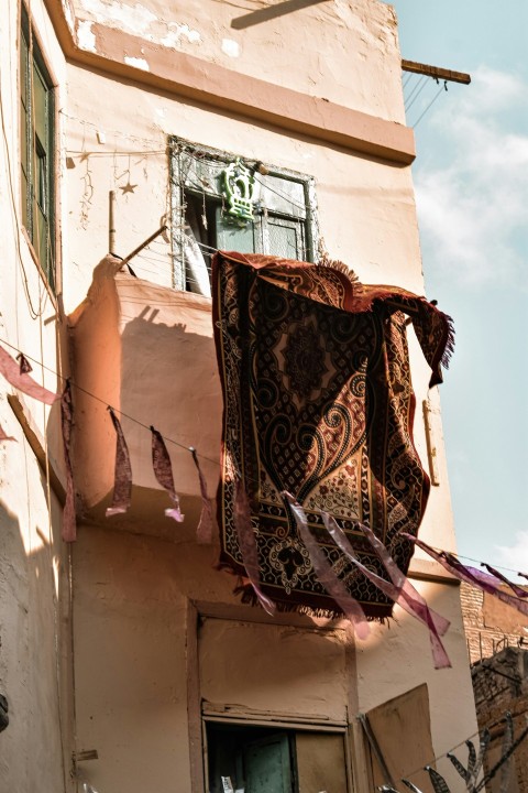 a building with a window and a rug hanging from the side of it