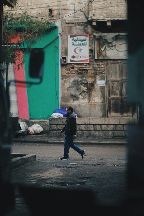 man in black jacket walking on sidewalk during daytime