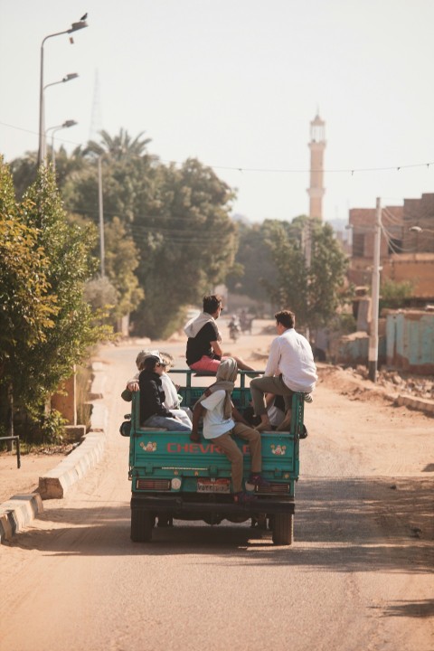 a group of people riding in the back of a green truck