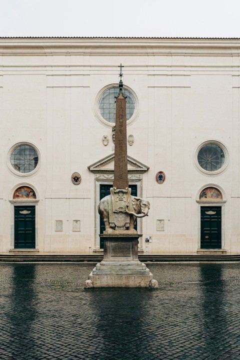 man holding rifle statue in front of white building