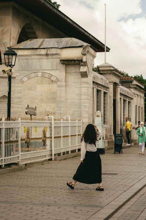 a woman in a black and white dress walking down a street 6q2zP5b