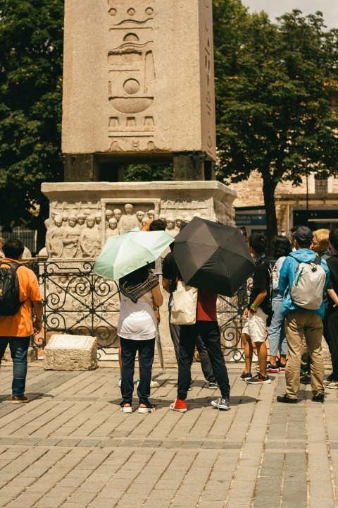 a group of people with umbrellas standing in front of a monument