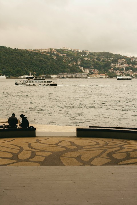 a couple of people sitting on a bench near the water PV2