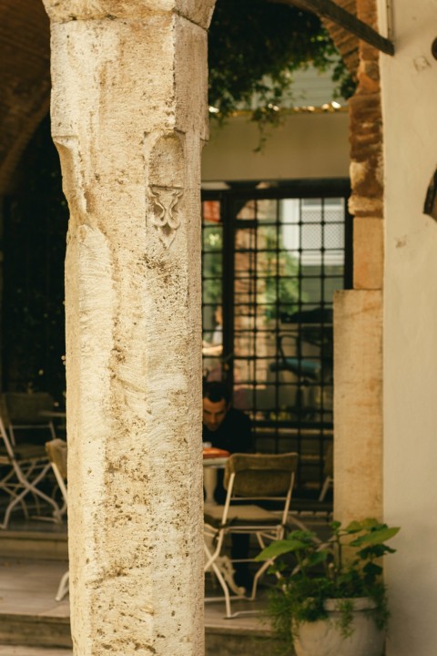 a cat sitting on a stone pillar in front of a building oVnrfQ