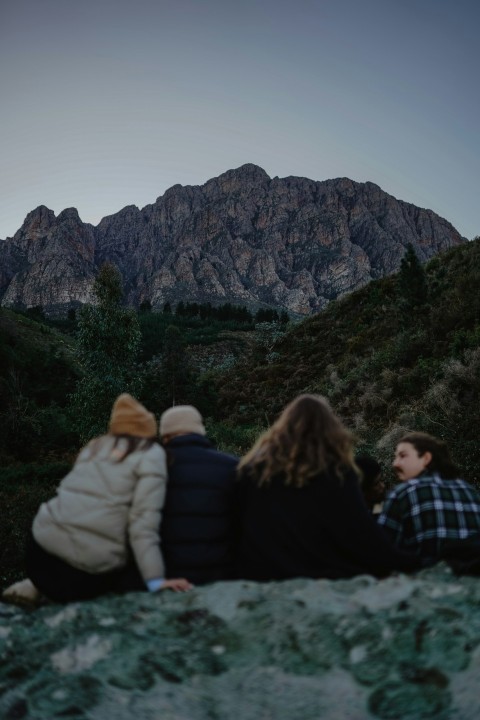 a couple of people sitting on top of a rock