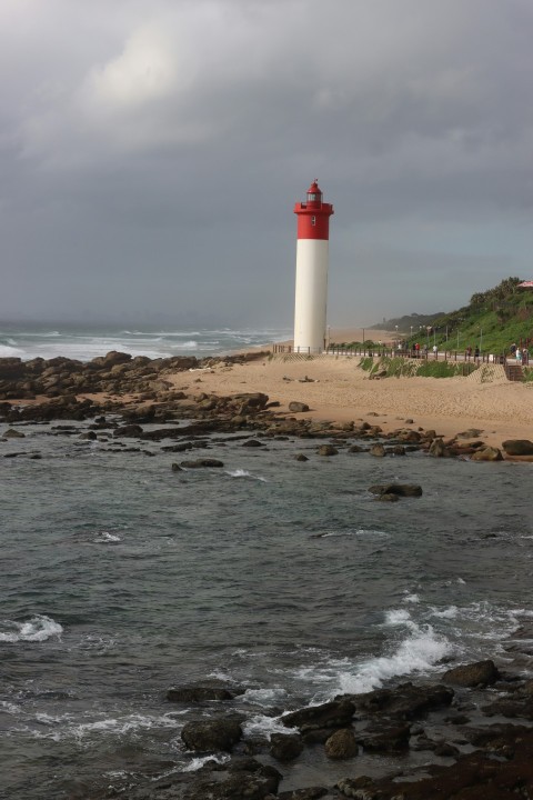 a red and white lighthouse sitting on top of a sandy beach