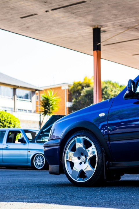 a blue car parked in a parking lot next to other cars