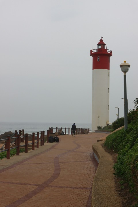 a red and white light house next to the ocean 9oc47wt_f