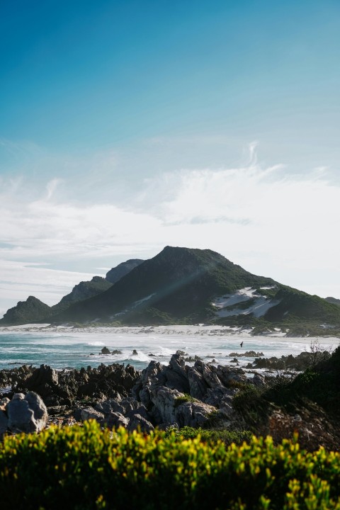 a rocky beach with a mountain in the background ELIi