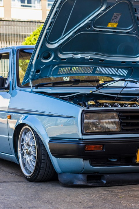 a blue car with its hood open in a parking lot