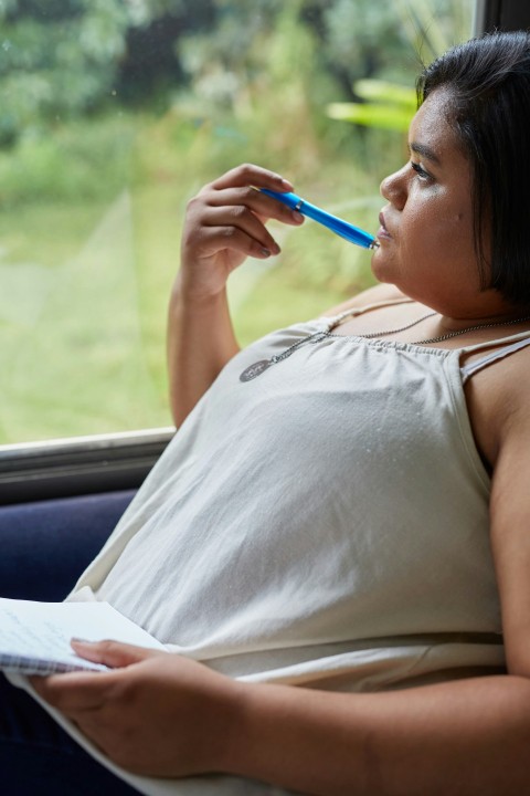 a woman sitting in a car holding a pen and paper