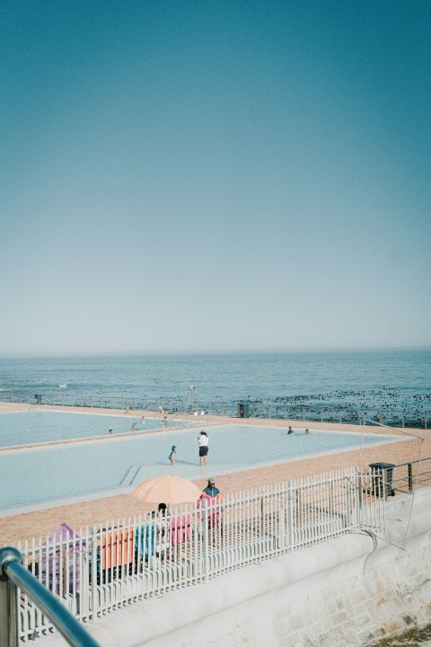 a group of people standing next to a swimming pool