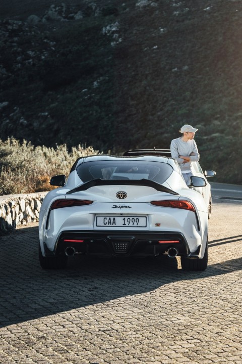 a man sitting on top of a white sports car