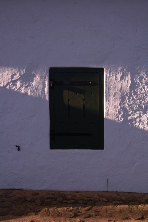 a white wall with a window and a black door