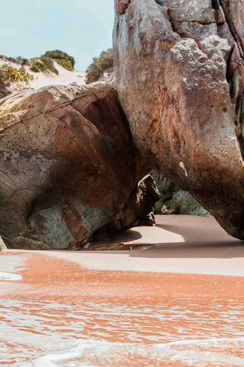 a large rock sticking out of a body of water QrqqhvUh