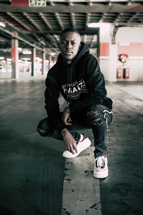 boy in black and white hoodie and blue denim jeans sitting on floor L