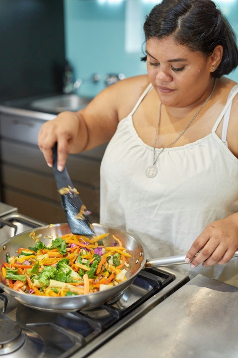 a woman is cooking vegetables