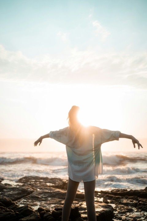 a woman standing on a rocky beach next to the ocean