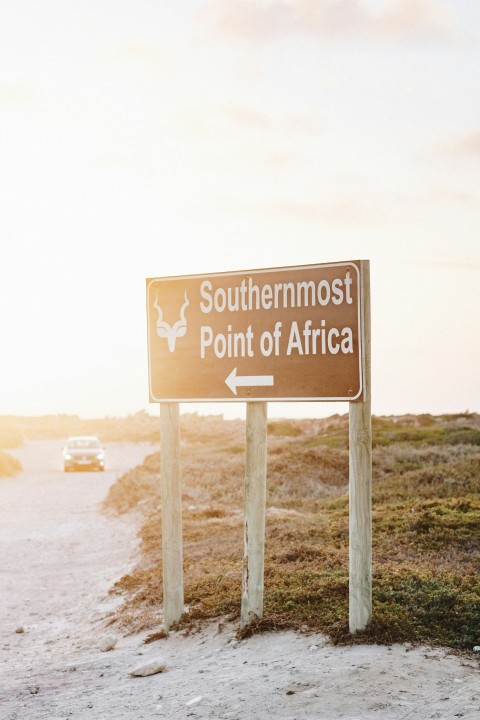 southermost point of africa road sign and white vehicle on road during daytime