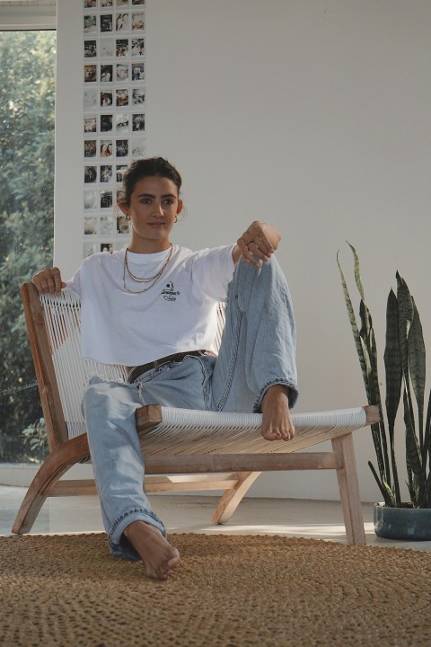 man in white crew neck t shirt sitting on brown wooden armchair