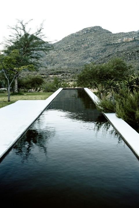 white boat on lake near green grass and mountain during daytime