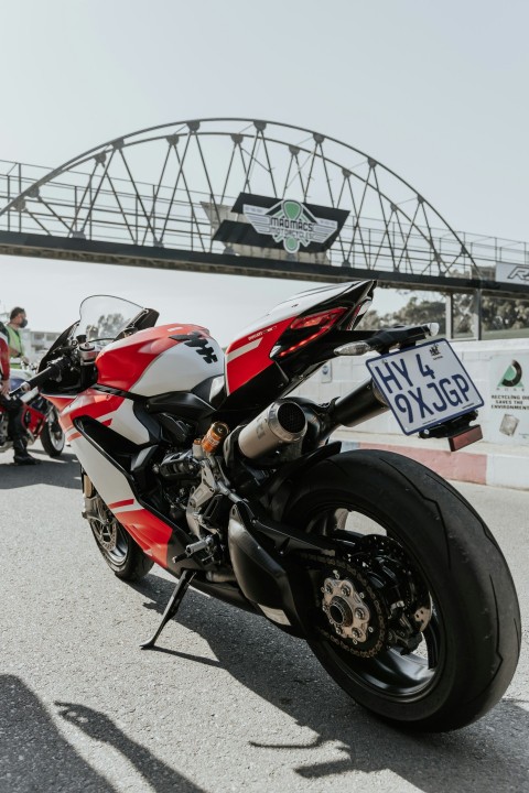 red and black sports bike parked on gray concrete road during daytime