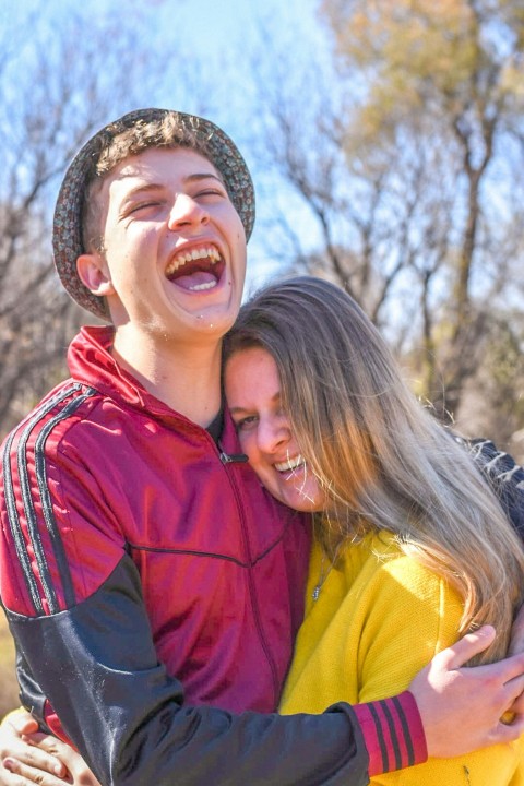 man in red polo shirt smiling beside woman in yellow jacket