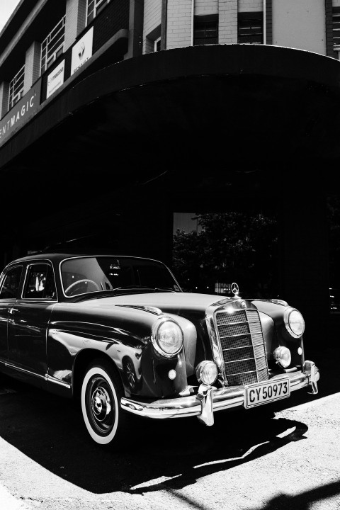 a black and white photo of a car parked in front of a building