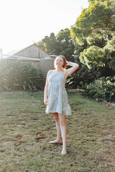 a woman standing in the grass with her hand on her head