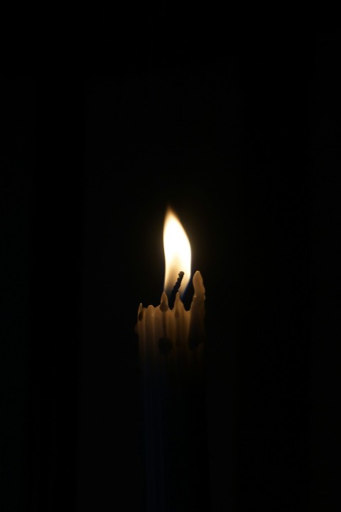 a lit candle in the dark with a black background