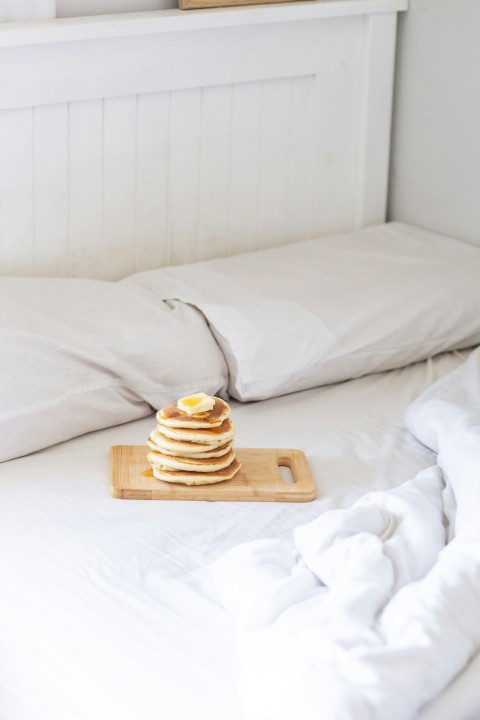 brown and white stripe ceramic mug on brown wooden tray on white bed DsZmPj9_