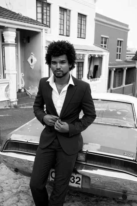 man in black suit standing beside car