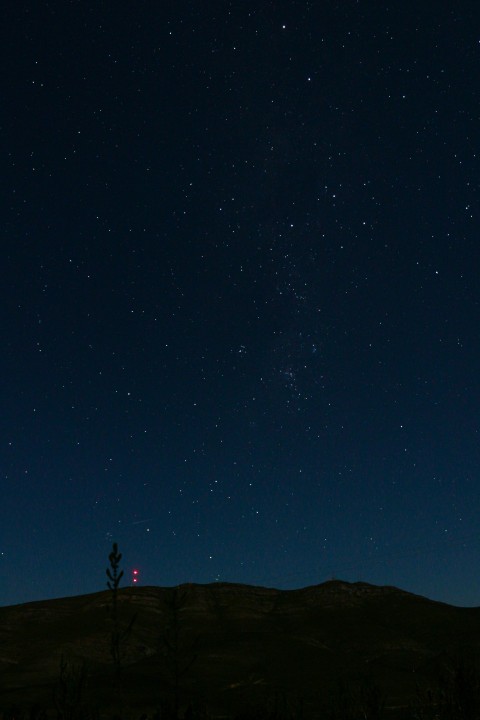 the night sky with stars above a hill