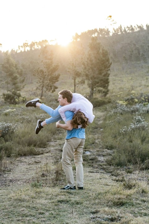 man in white shirt carrying woman in blue jacket during daytime aZxFtOC