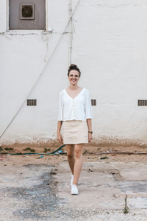 woman standing on concrete pavement in front of white printed wall building