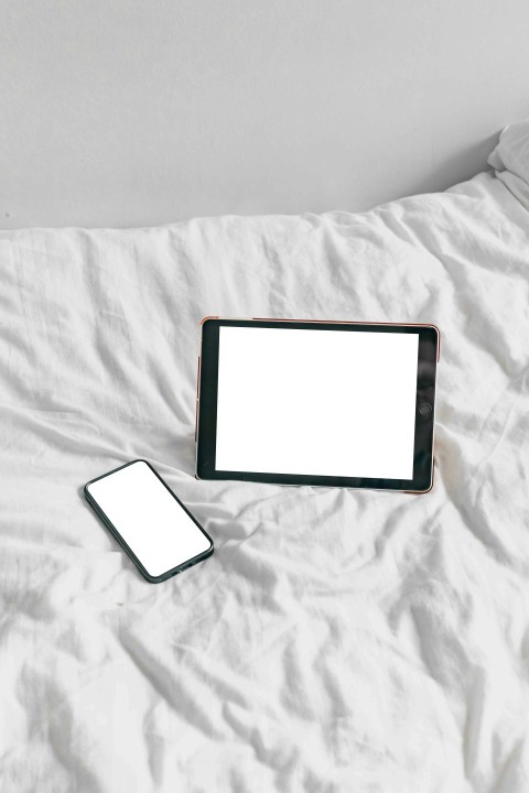 a tablet and a cell phone on a bed