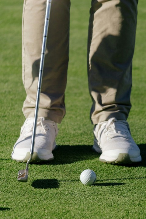 a man standing on top of a green field next to a golf ball