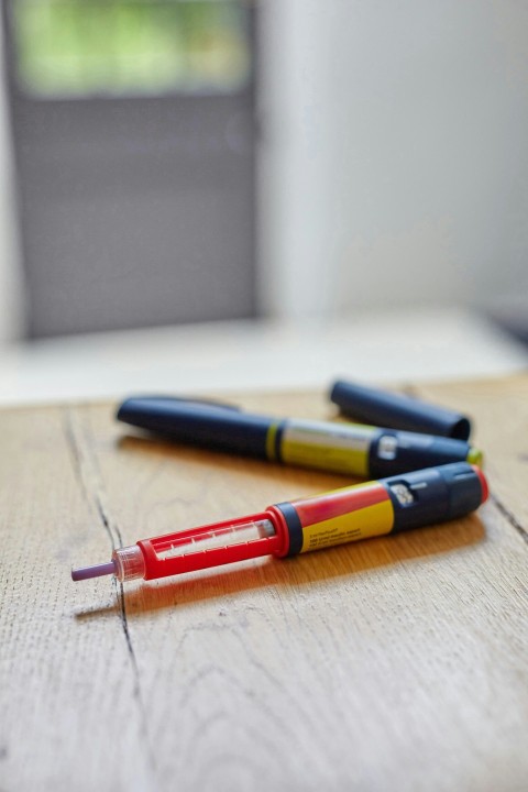 a couple of insulin pens sitting on top of a wooden table