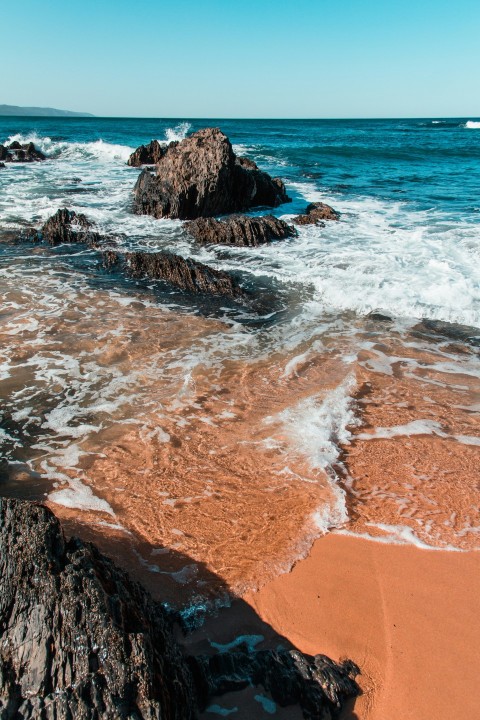 brown rocky shore with ocean waves during daytime