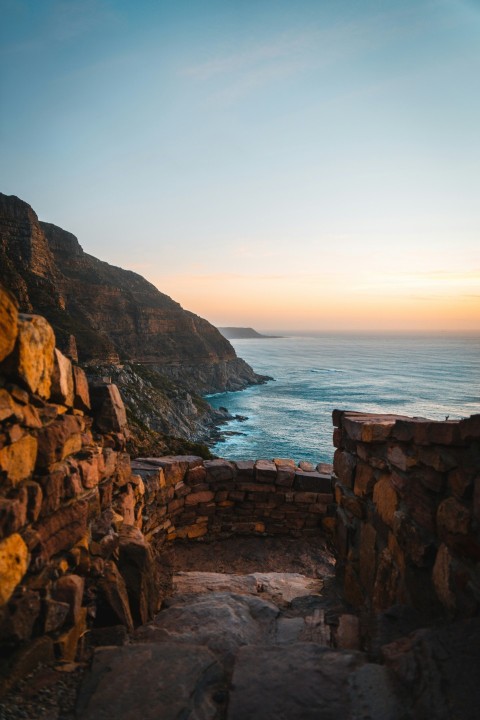 brown rocky mountain beside sea during daytime