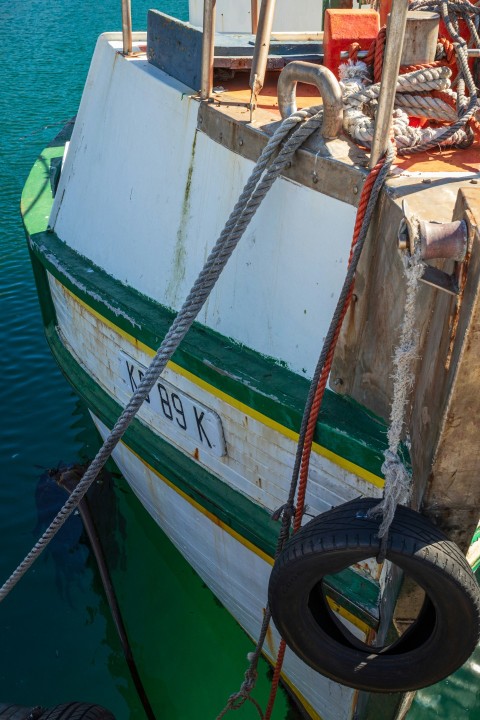 a white and green boat tied up to a dock