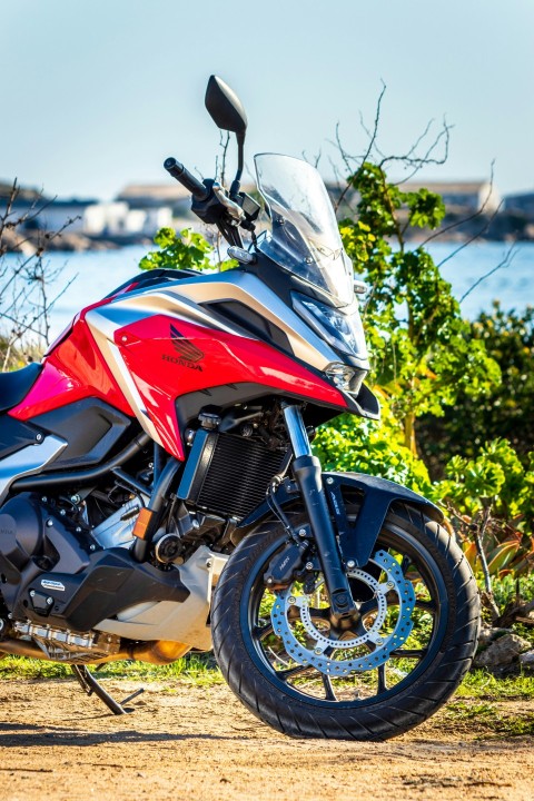 a red and silver motorcycle parked on a dirt road