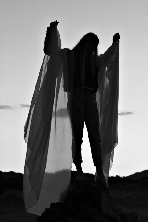 man in black jacket and pants standing on sand